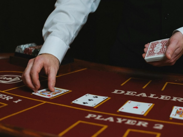 Dealer placing cards on a red felt casino table.