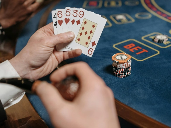 Player holding blackjack cards and a pipe at a casino table.