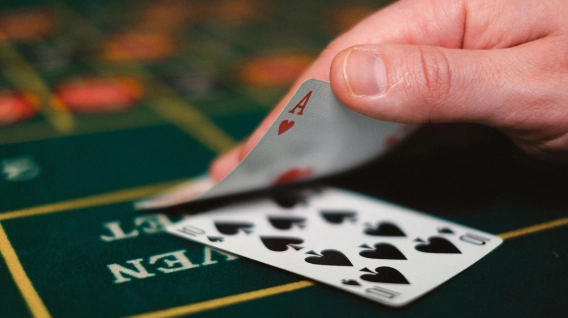 Hand revealing an ace in a casino card game.