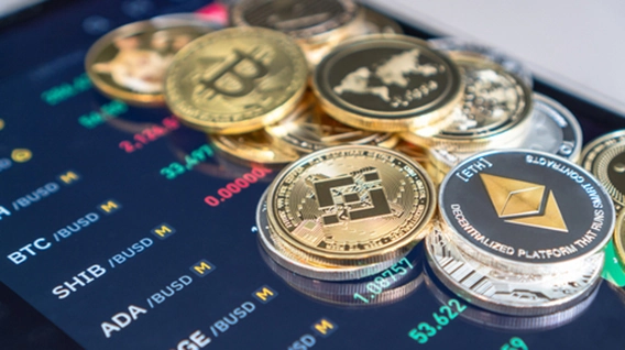 Cryptocurrency coins displayed on a screen showing market data.