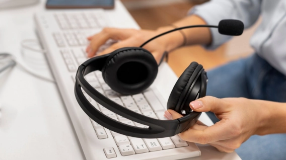 A customer service agent holding a headset while typing on a keyboard.