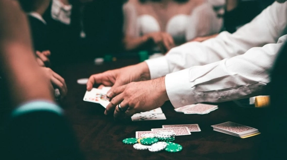 Dealer handing out cards at a table with chips and players.