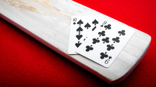 Ten of spades and nine of clubs on a wooden board.